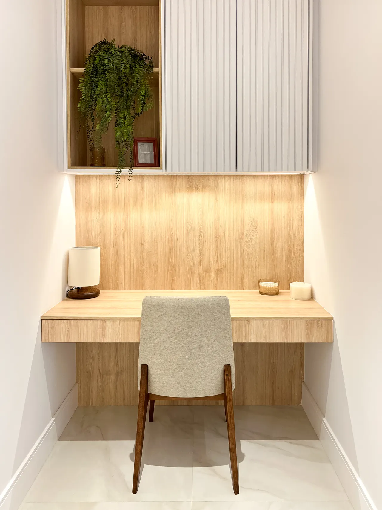 A wooden desk and chair in a light home workspace.